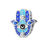 Ce charm en argent 925 représente une main Hamsa stylisée, entièrement décorée de nuances de bleu et de turquoise, symbole de protection et de chance. Au centre, un grand œil noir et blanc est entouré de cristaux transparents et de pierres bleues, tandis que des étoiles et un croissant de lune complètent l’ambiance mystique du motif.

Caractéristiques :

- Matière : Argent 925 avec émaux bleu et turquoise, cristaux transparents et bleus.
- Design : Main Hamsa en relief avec œil central, étoiles et lune, dét