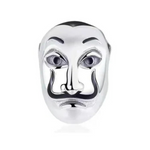 Exprimez votre côté audacieux et mystérieux avec le Charm Masque de La Casa de Papel, finement conçu en argent 925. Inspiré du célèbre masque emblématique de la série à succès, ce charm symbolise la rébellion, la liberté et le courage de rêver en grand. Avec ses détails soigneusement sculptés, ce bijou est un hommage parfait aux fans de l’univers de La Casa de Papel.

Que vous soyez un passionné de la série ou que vous souhaitiez ajouter une touche de mystère et de style à votre bracelet, ce charm sera une 