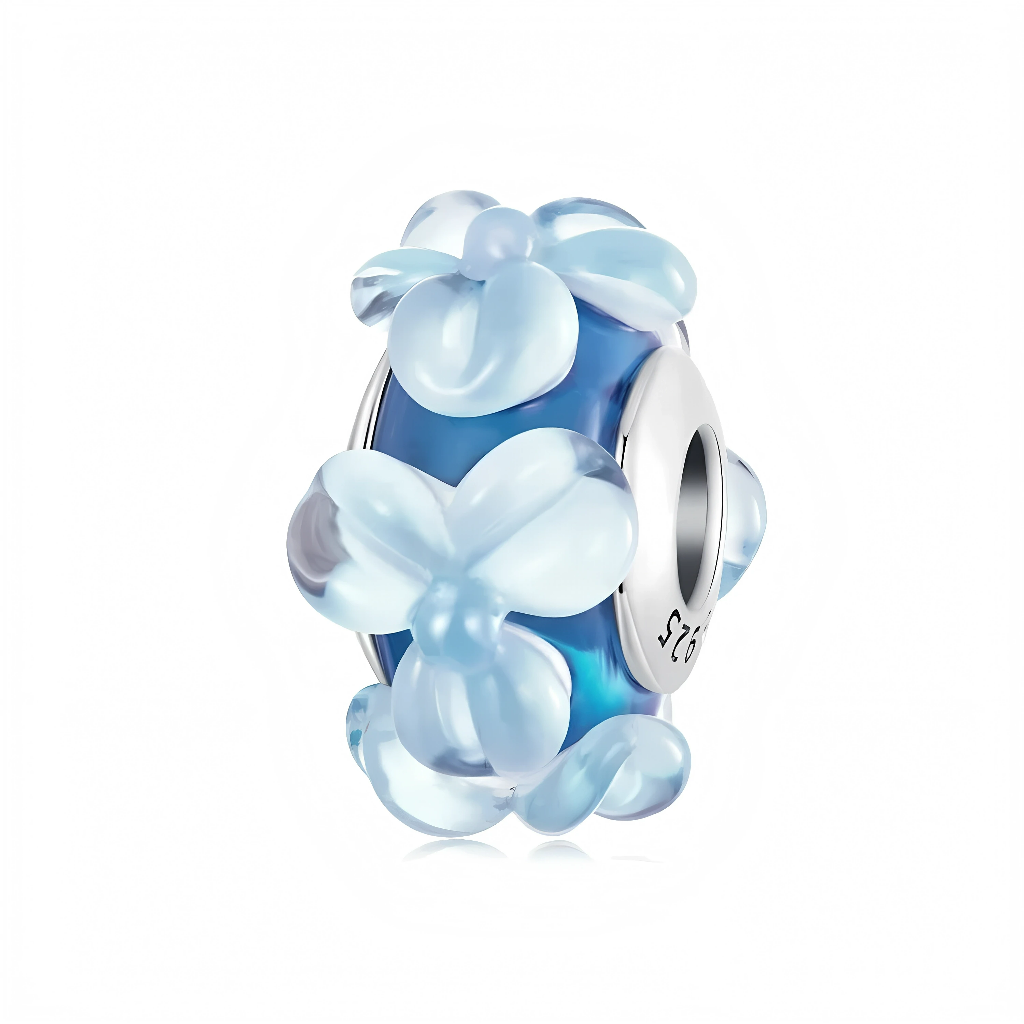 Le cœur de la perle est un tube de verre bleu profond légèrement translucide, qui rappelle la couleur de l’océan ou d’un ciel d’été. Tout autour, des fleurs en 3D d’un bleu glacé semblent éclore à la surface du verre, créant du volume et un effet « bouquet » tout en douceur. Le noyau en argent 925 permet d’associer facilement ce charm à d’autres perles Murano ou à des charms argent pour un bracelet riche en textures.