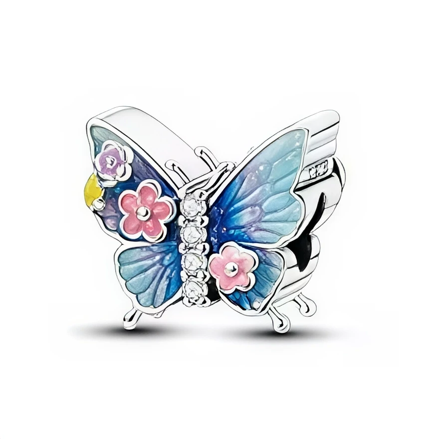Ce charm en forme de papillon déploie de larges ailes en argent 925, décorées d’émaux dégradés bleu et turquoise pour un effet lumineux et aérien. De petites fleurs roses et violettes se posent sur les ailes, tandis qu’une ligne de cristaux clairs dessine le corps du papillon, apportant une touche d’éclat parfaite pour égayer un bracelet ou un collier.