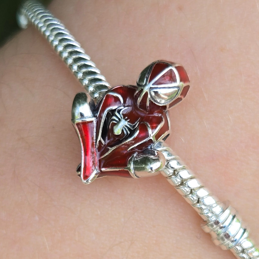 Apportez une dose d’énergie héroïque à votre collection avec ce charm unique inspiré du célèbre Spider-Man. En position accroupie iconique, vêtu de son costume rouge et noir avec l’araignée blanche emblématique sur la poitrine, il incarne parfaitement l’esprit courageux et dynamique du super-héros. Ses détails soignés et ses finitions éclatantes en font une pièce incontournable qui séduira autant les passionnés de Marvel que les amateurs de bijoux originaux.