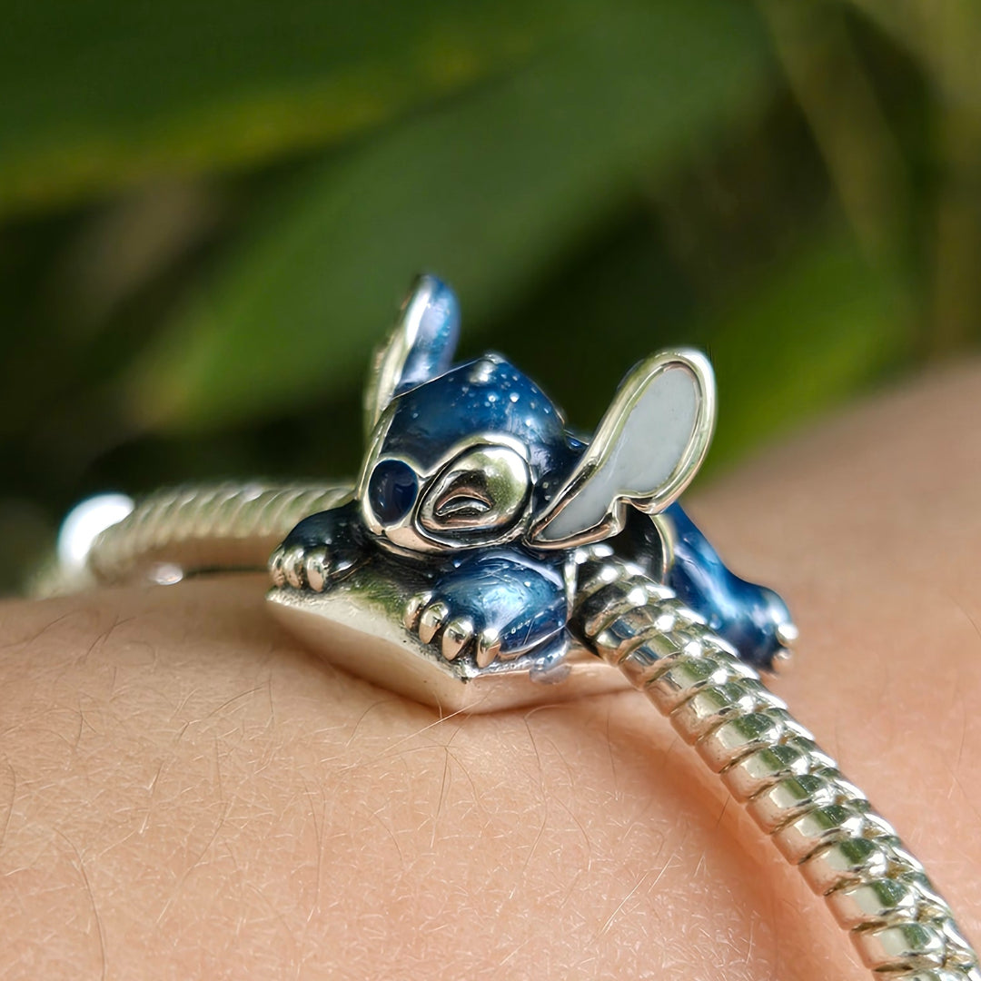 Ajoutez une touche de douceur et de fantaisie à votre collection avec ce charm irrésistible de Stitch endormi sur un oreiller. Cette scène attendrissante capture toute la tendresse du célèbre extraterrestre de Lilo &amp; Stitch, paisiblement installé pour une sieste bien méritée.

Fabriqué en argent 925, ce charm se distingue par ses finitions brillantes et ses détails minutieusement travaillés : les nuances bleues emblématiques de Stitch, ses grandes oreilles et ses petites griffes reposant délicatement su