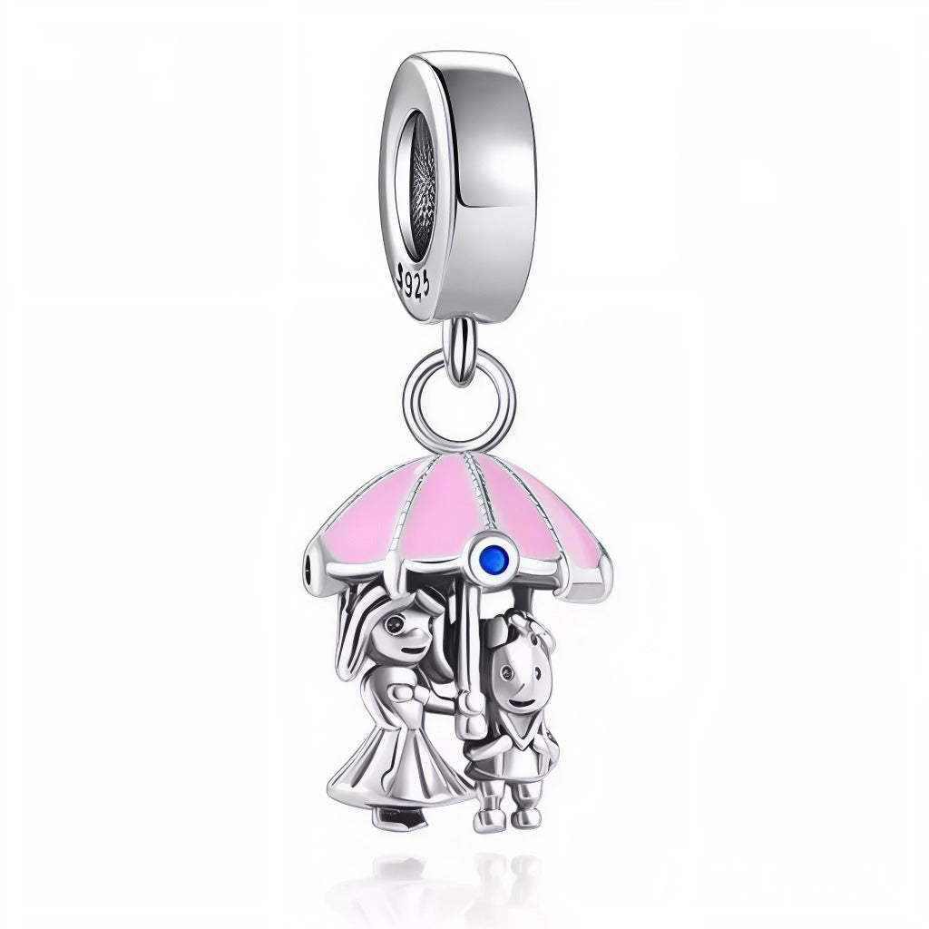 Laissez-vous séduire par ce charm raffiné représentant un couple enlacé sous un parapluie rose, symbole intemporel de tendresse et de protection. Conçu en argent 925, il met en scène deux personnages adorables, protégés ensemble de la pluie sous un dôme pastel orné d’un petit cristal bleu étincelant. Un bijou tout en finesse pour célébrer l’amour, le partage et les moments précieux à deux, idéal à offrir ou à ajouter à votre collection pour exprimer votre côté romantique au quotidien. Compatible avec la plu