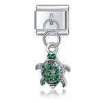 Ce charm italien pendentif représente une tortue délicate ornée de strass verts scintillants, symbole de longévité et de nature. Fabriqué en acier inoxydable de haute qualité avec une finition argentée élégante, il allie robustesse et finesse des détails pour un rendu raffiné et lumineux. Facile à fixer, il s’adapte parfaitement à nos bracelets composés de 17 maillons extensibles et réglables, convenant à toutes les tailles de poignet. Compatible avec tous nos charms italiens, ce bijou étincelant est idéal 