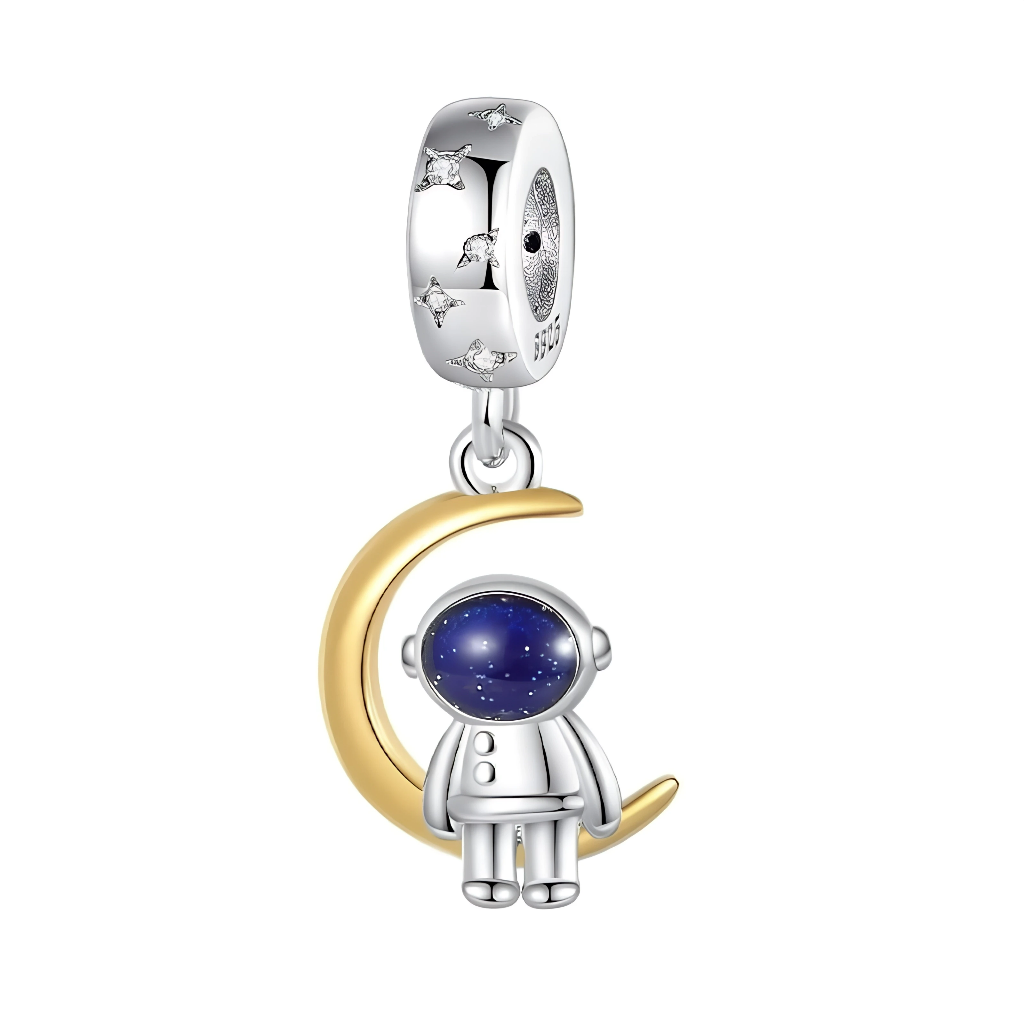 La bélière en argent est décorée de petites étoiles scintillantes, comme un ciel nocturne miniaturisé au-dessus du pendentif. En dessous, un croissant de lune doré accueille un astronaute en combinaison argentée dont le casque bombé bleu nuit évoque un ciel étoilé profond. L’ensemble crée un bijou poétique et inspirant qui rappelle qu’il ne faut jamais cesser de viser la lune et de poursuivre ses rêves.