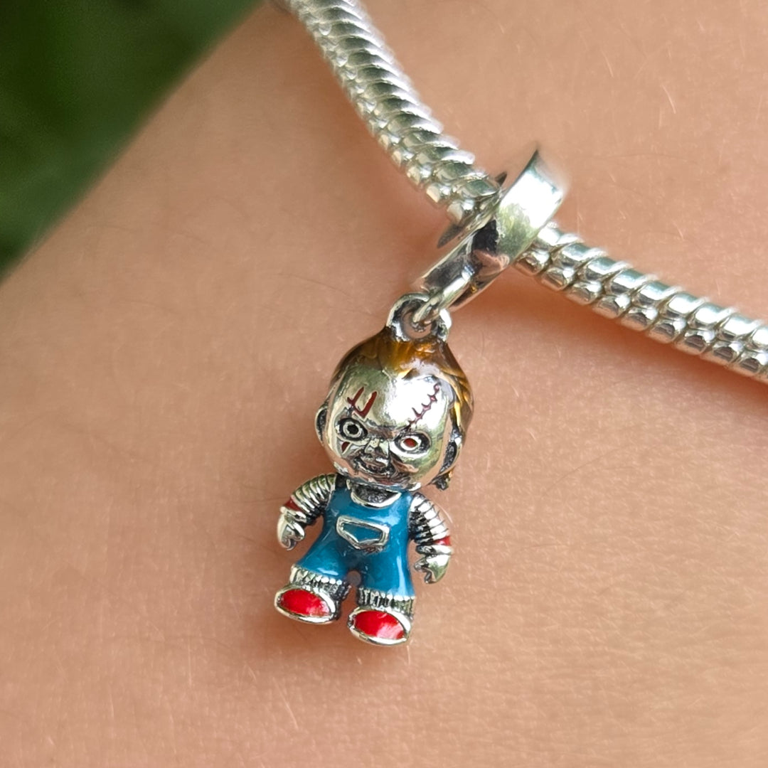 Osez afficher votre passion pour les films d’horreur avec ce charm pendentif à l'effigie de Chucky, réalisé en&nbsp;argent 925&nbsp;et minutieusement coloré à la main. Ce bijou unique reprend fidèlement les détails du célèbre personnage : cicatrices emblématiques, salopette bleue et regard malicieux, pour un rendu à la fois effrayant et collector. Idéal pour personnaliser un bracelet à charms ou un collier, ce pendentif est le must-have des amateurs de pop culture et de bijoux originaux. Une pièce qui prome