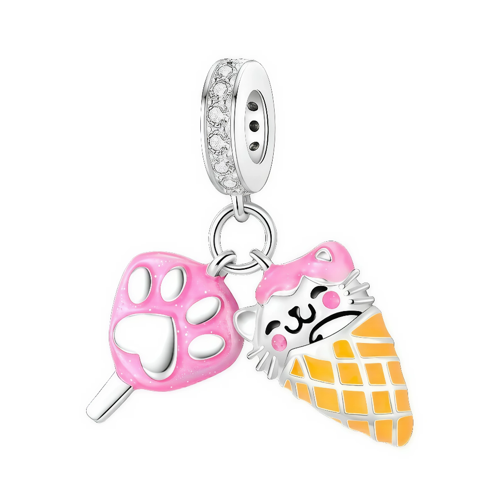 La bélière en argent 925 est pavée de petits zircons clairs et relie deux breloques mobiles. L’une représente une sucette en forme d’empreinte de patte rose, l’autre un cornet de glace jaune avec une tête de chat argentée recouverte de glace rose, aux joues et museau noirs dessinés façon kawaii.