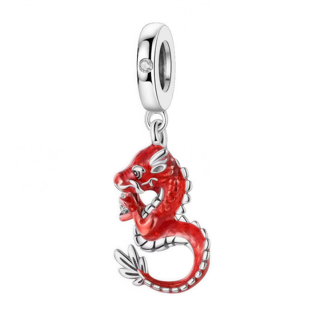 Ce pendentif spectaculaire représente un dragon asiatique enroulé, recouvert d’un émail rouge aux reflets profonds et relevé de détails argentés fins. L’expression féroce, la position dynamique et la perle tenue dans ses griffes rappellent la mythologie chinoise, où le dragon apporte prospérité et succès. La bélière incrustée d’un zircon transparent ajoute une touche d’éclat supplémentaire. Un bijou statement pour une collection thème Asie, force ou spiritualité.
