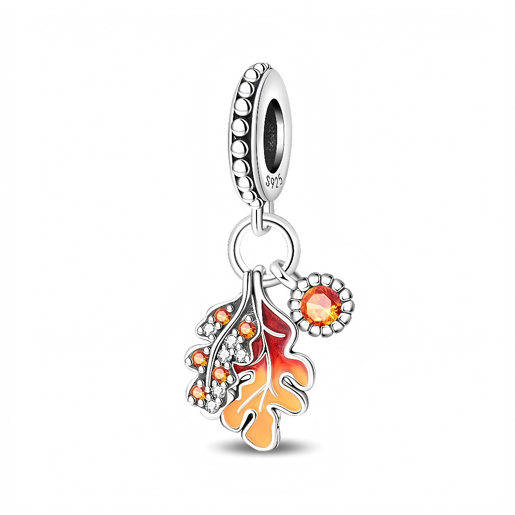 La bélière en argent 925 est ornée d’un motif de petites perles en relief et porte l’inscription S925 à l’intérieur. Elle soutient deux feuilles finement nervurées émaillées dans des tons chauds, ponctuées de mini‑cristaux orangés, ainsi qu’un petit médaillon rond serti d’une pierre orange brillante qui rappelle la lumière du soleil couchant.
