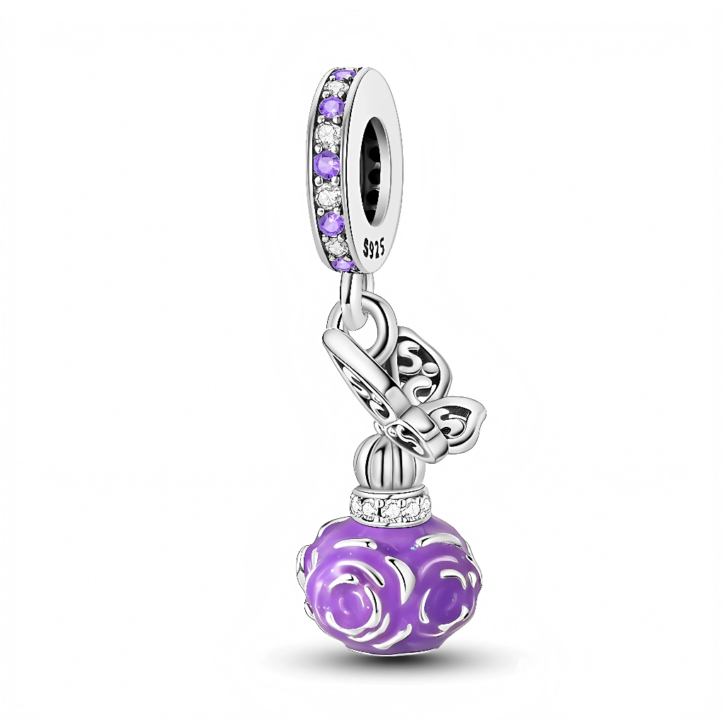La bélière est pavée d’oxydes de zirconium violets et blancs qui apportent beaucoup d’éclat et rappellent des éclats de lumière sur un flacon en cristal. En dessous, un papillon ajouré argenté se pose sur le « bouchon » du flacon, lui‑même cerclé d’un rang de petites pierres claires. Le corps du flacon est une boule violette sculptée de roses en relief, comme un parfum floral encapsulé dans un bijou miniature.