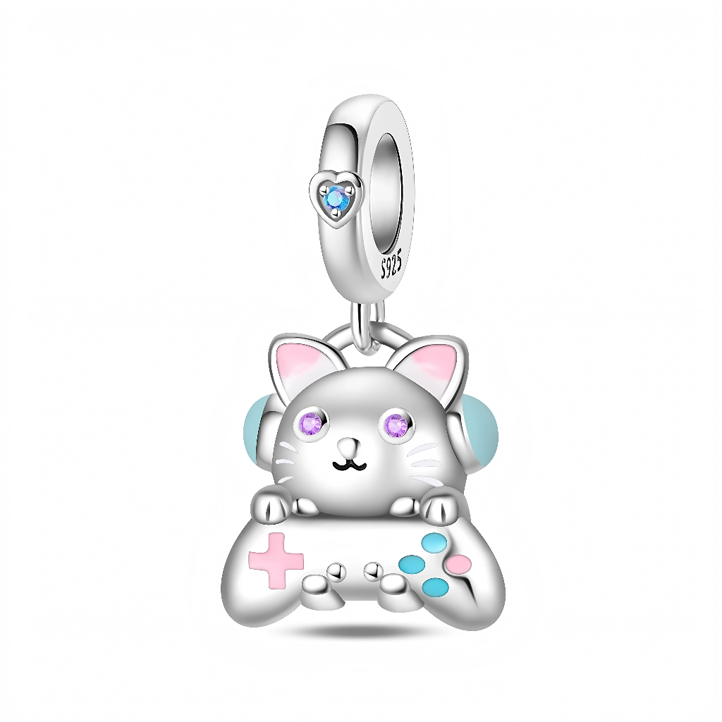 La bélière en argent 925 est décorée d’un petit cœur serti d’un cristal bleu, d’où pend un chat stylisé aux yeux violets scintillants, oreilles rosées et gros casque bleu clair. Entre ses pattes, le chat tient une manette de jeu avec croix directionnelle rose et boutons turquoise, rappelant l’univers coloré du gaming.