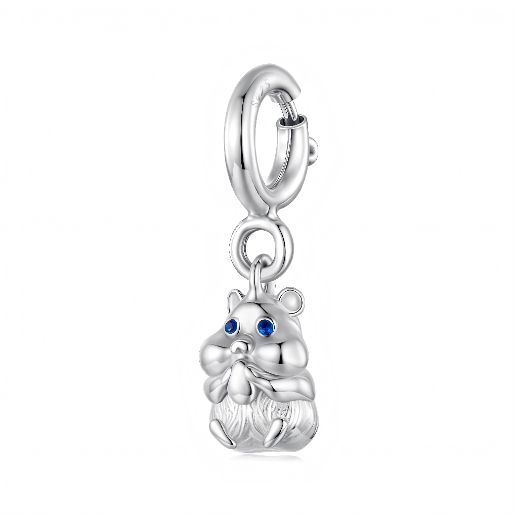 Le hamster est sculpté avec des joues bien rondes, de petites oreilles et une fourrure texturée sur le bas du corps, ce qui renforce son côté réaliste et attendrissant. Ses yeux sont deux pierres bleues brillantes qui apportent une touche de couleur, tandis qu’un anneau lisse et un fermoir type mousqueton permettent de l’accrocher facilement à un bracelet, un collier ou même un porte-clés. Ce motif convient particulièrement aux amoureux des rongeurs de compagnie, comme les hamsters nains ou syriens.