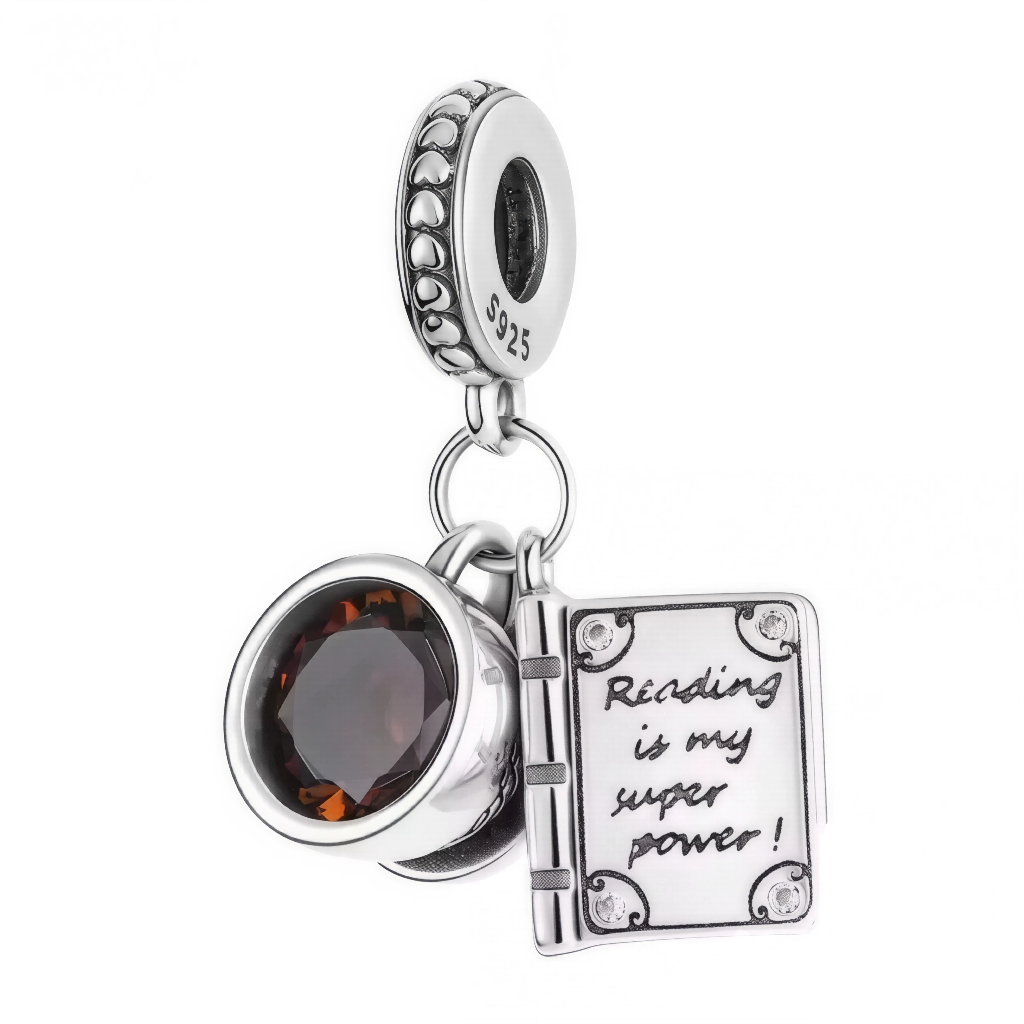 Ce charm réunit éclat et message inspirant. D’un côté, une gemme taille coussin couleur thé apporte profondeur et lumière; de l’autre, un mini livre ouvert révèle la gravure motivante "Reading is my super power!". La bélière est décorée d’une frise de cœurs, clin d’œil tendre à la passion de la lecture. Idéal pour bibliophiles, professeurs, étudiants ou pour marquer un cap littéraire.

