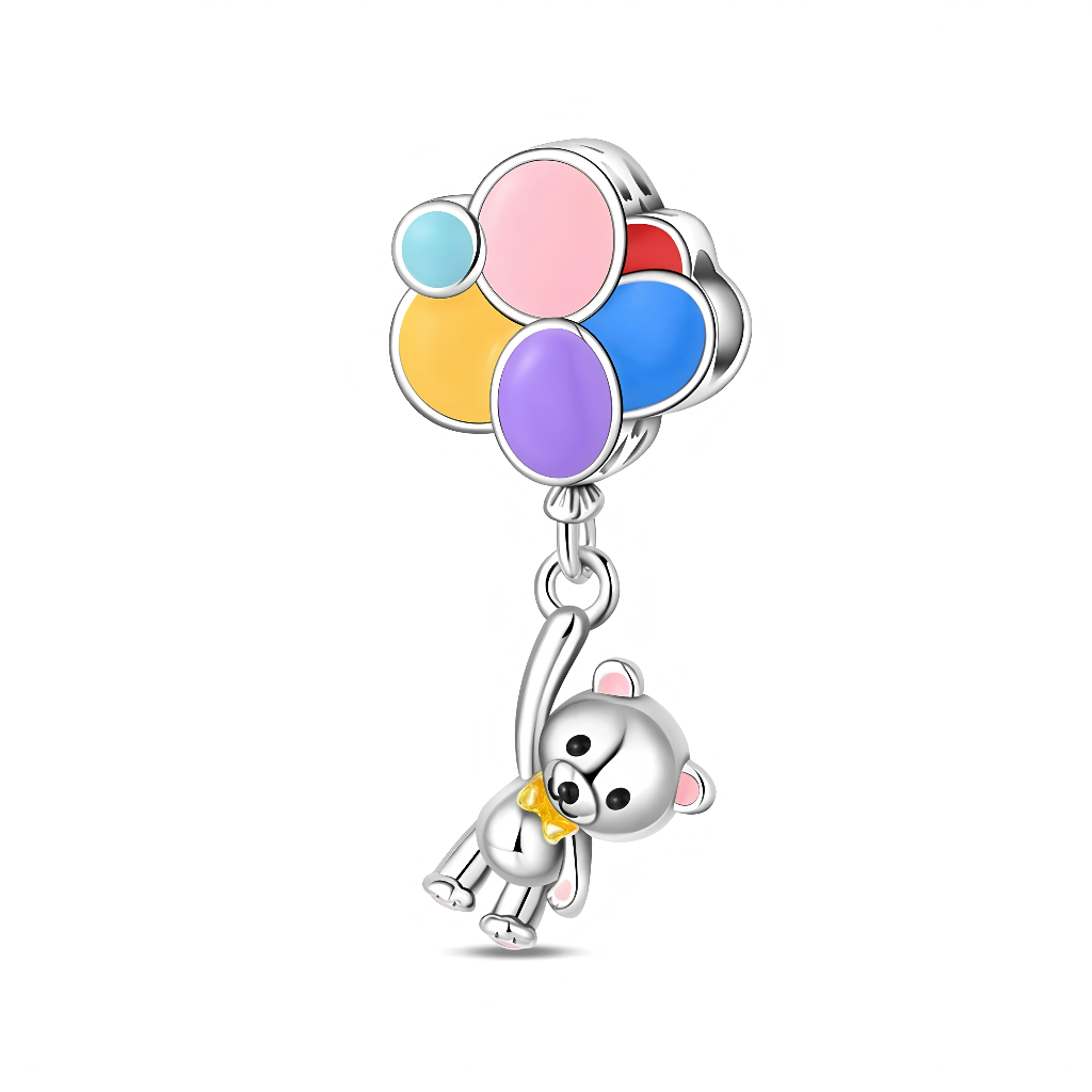 La partie supérieure du charm forme un bouquet de ballons émaillés dans des tons pastel jaune, rose, violet, bleu et turquoise, réunis dans une pièce pleine qui glisse sur le bracelet. En dessous, un ourson argenté au nœud papillon jaune se balance en tenant les ballons d’une patte, avec de subtils accents d’émail rose aux oreilles.
