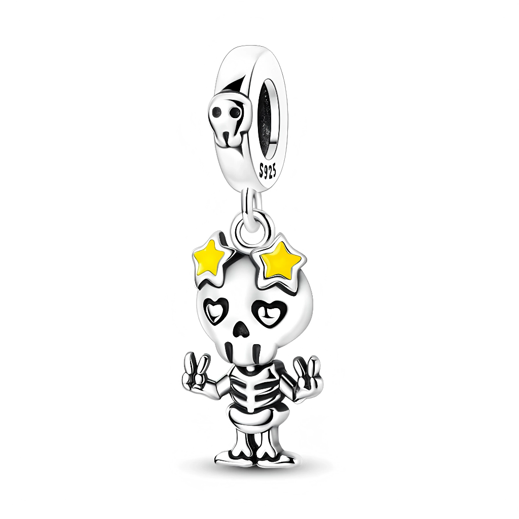 Ce charm pendant en argent 925 représente un petit squelette cartoon faisant le signe « peace » des deux mains, avec des yeux en forme de cœur et deux étoiles jaunes sur la tête