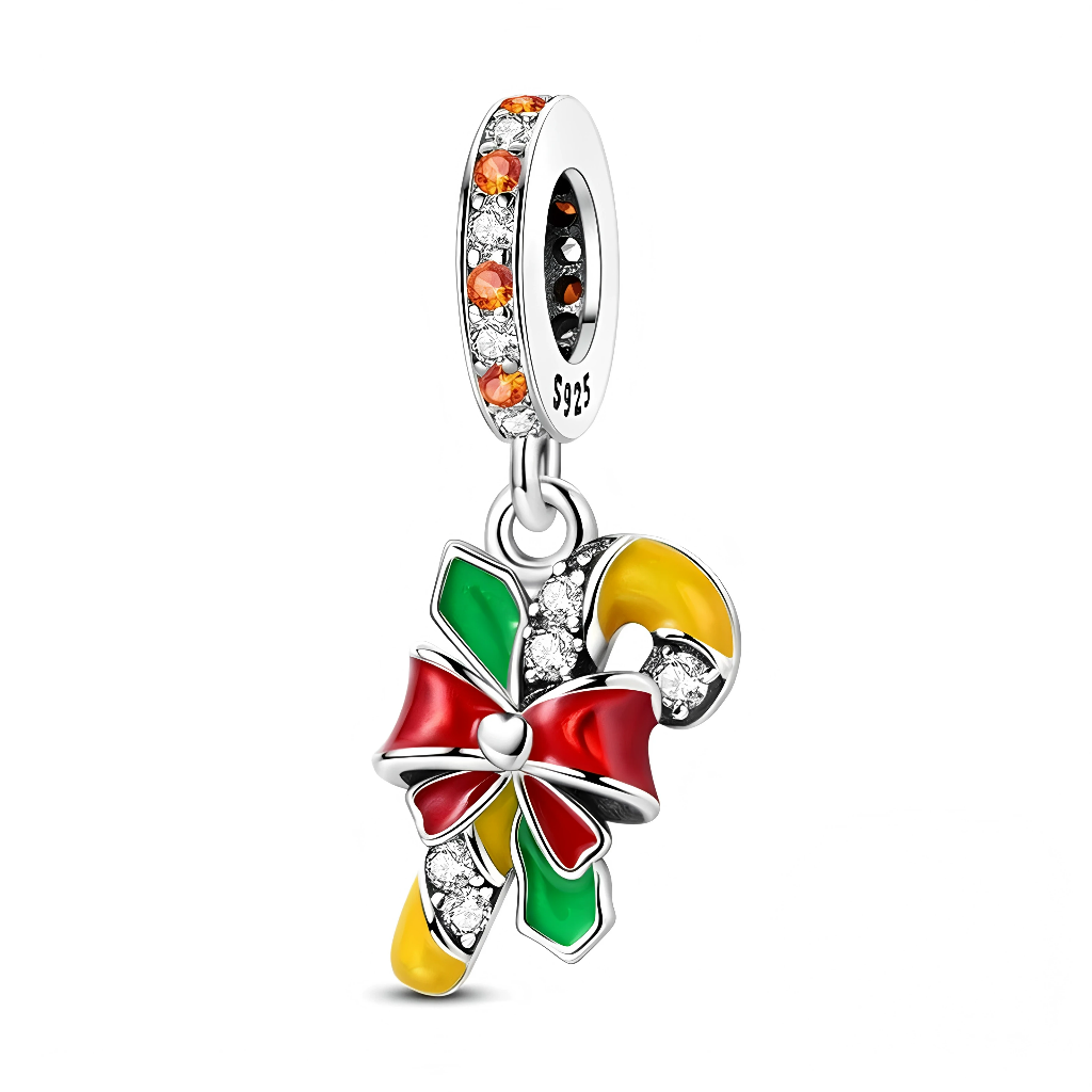 La bélière est sertie d’oxydes de zirconium orange et transparents, qui rappellent les lumières chaudes d’un marché de Noël. En dessous, le sucre d’orge alterne des parties jaunes émaillées et des zones pavées de pierres claires, rehaussé d’un grand nœud rouge et de feuilles vertes façon houx, pour un look de décoration de sapin miniature.