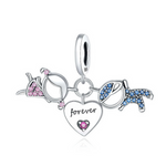 Ce charm en argent 925 représente un couple stylisé : une silhouette féminine pavée de cristaux roses d’un côté, une silhouette masculine sertie de pierres bleues de l’autre, reliées par un cœur central gravé du mot « forever » et orné d’un petit cristal rose. Les trois éléments sont suspendus à un grand anneau mobile fixé à une bélière lisse marquée S925, ce qui crée un joli mouvement lorsque le bracelet bouge.