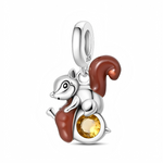 L’écureuil lisse en argent présente une grande queue recourbée d’émail brun et des pattes également émaillées, ce qui apporte une touche chaleureuse d’automne. Le gland rond sous ses pattes intègre un cristal jaune facetté qui capte la lumière, évoquant une noisette dorée ou un trésor qu’il protège.