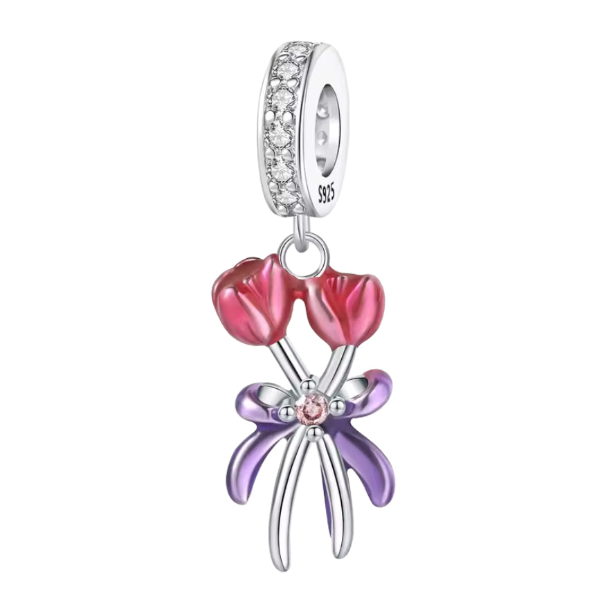 Ce charm met en scène deux tulipes aux pétales émaillés rose dégradé, réunies par de fines tiges argent qui se croisent. Un ruban violet brillant forme un nœud généreux au centre, serti d’une petite pierre rose qui attire la lumière, tandis que la bélière est entièrement pavée de zircons clairs pour un effet très lumineux. Idéal pour symboliser l’amour, la gratitude ou un joli “merci” fleuri au poignet.