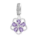 Ce charm met en valeur une fleur graphique composée de cinq pétales cœur facettés violet améthyste, retenus par un délicat serti griffe autour d’un centre scintillant blanc. La monture ajourée en argent dessine un contour léger, tandis que la bélière entièrement pavée de zircons clairs ajoute une ligne de lumière supplémentaire sur le bracelet. Une pièce élégante et féminine, parfaite pour illuminer une composition florale ou romantique.