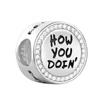Ce charm pendentif drôle immortalise la réplique légendaire de Joey dans Friends : “How You Doin’?”, écrite en lettres manuscrites noires espiègles sur un médaillon rond blanc enamel, entouré d’un cercle de strass étincelants pour un effet glamour. L’anneau supérieur serti de cristaux poinçonné « S925 » en argent sterling offre une fixation Pandora-compatible, avec une petite couronne discrète ajoutant une touche royale à l’humour. Ce design capture le flirt charismatique de Joey Tribbiani, parfait pour déc