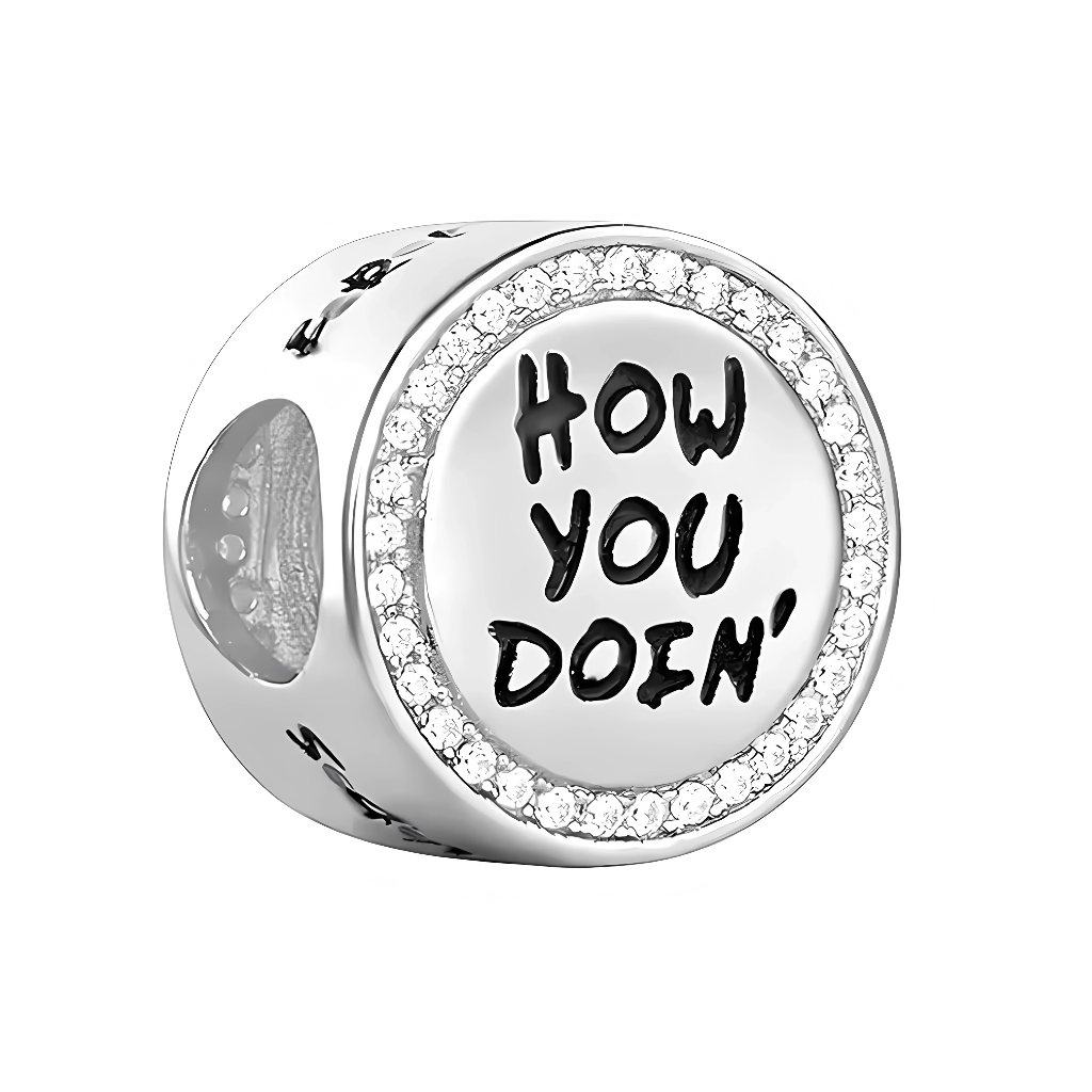 Ce charm pendentif drôle immortalise la réplique légendaire de Joey dans Friends : “How You Doin’?”, écrite en lettres manuscrites noires espiègles sur un médaillon rond blanc enamel, entouré d’un cercle de strass étincelants pour un effet glamour. L’anneau supérieur serti de cristaux poinçonné « S925 » en argent sterling offre une fixation Pandora-compatible, avec une petite couronne discrète ajoutant une touche royale à l’humour. Ce design capture le flirt charismatique de Joey Tribbiani, parfait pour déc