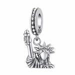Ce charm pendentif iconique reproduit la Statue de la Liberté en argent 925 poli, torche levée bien haut symbolisant l’espoir et la liberté, couronne rayonnante et robe drapée aux plis réalistes. Les détails ciselés capturent fidèlement le visage serein et la posture accueillante de Lady Liberty, gardienne de New York. L’anneau supérieur pavé de zircons étincelants assure une fixation premium sur les bracelets.