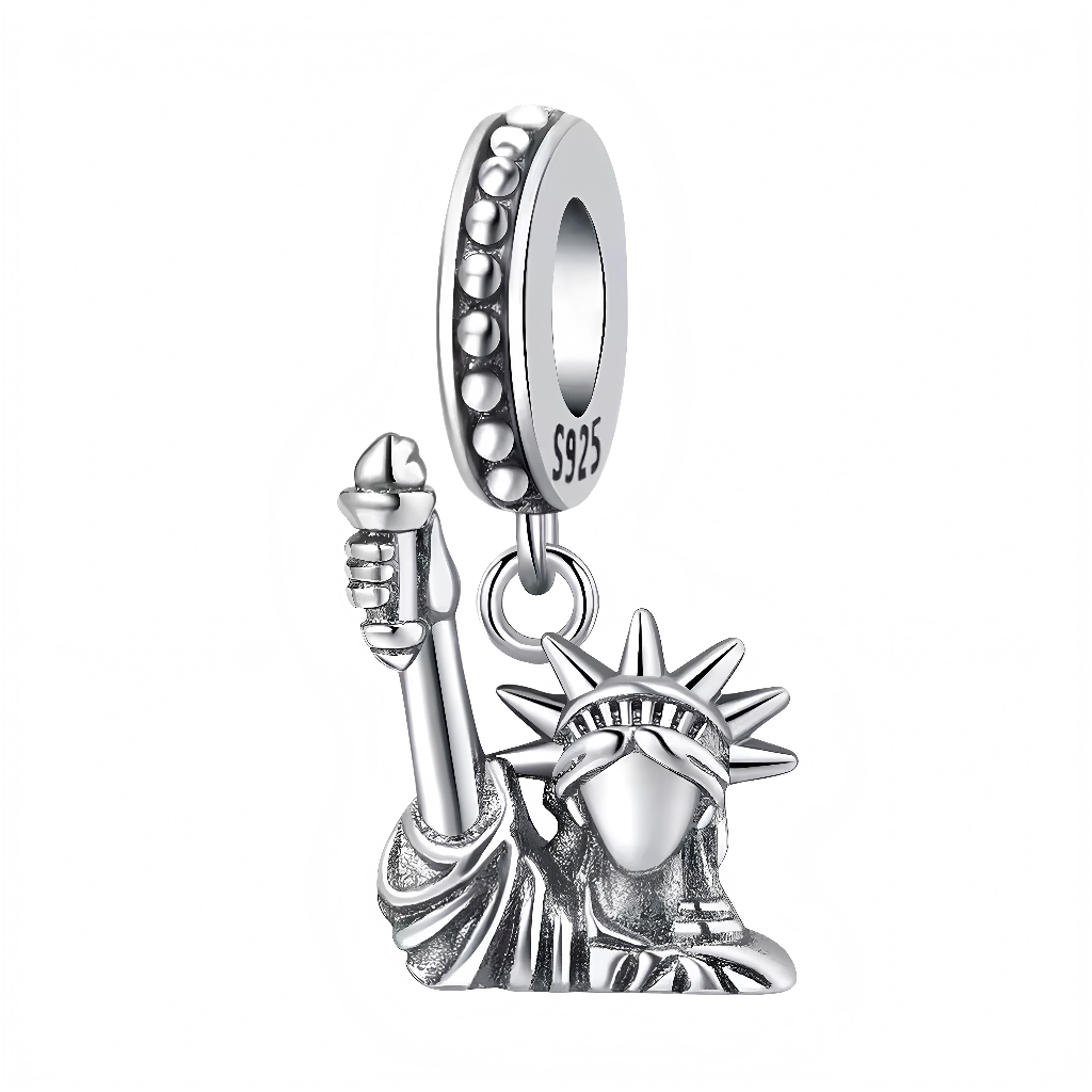 Ce charm pendentif iconique reproduit la Statue de la Liberté en argent 925 poli, torche levée bien haut symbolisant l’espoir et la liberté, couronne rayonnante et robe drapée aux plis réalistes. Les détails ciselés capturent fidèlement le visage serein et la posture accueillante de Lady Liberty, gardienne de New York. L’anneau supérieur pavé de zircons étincelants assure une fixation premium sur les bracelets.