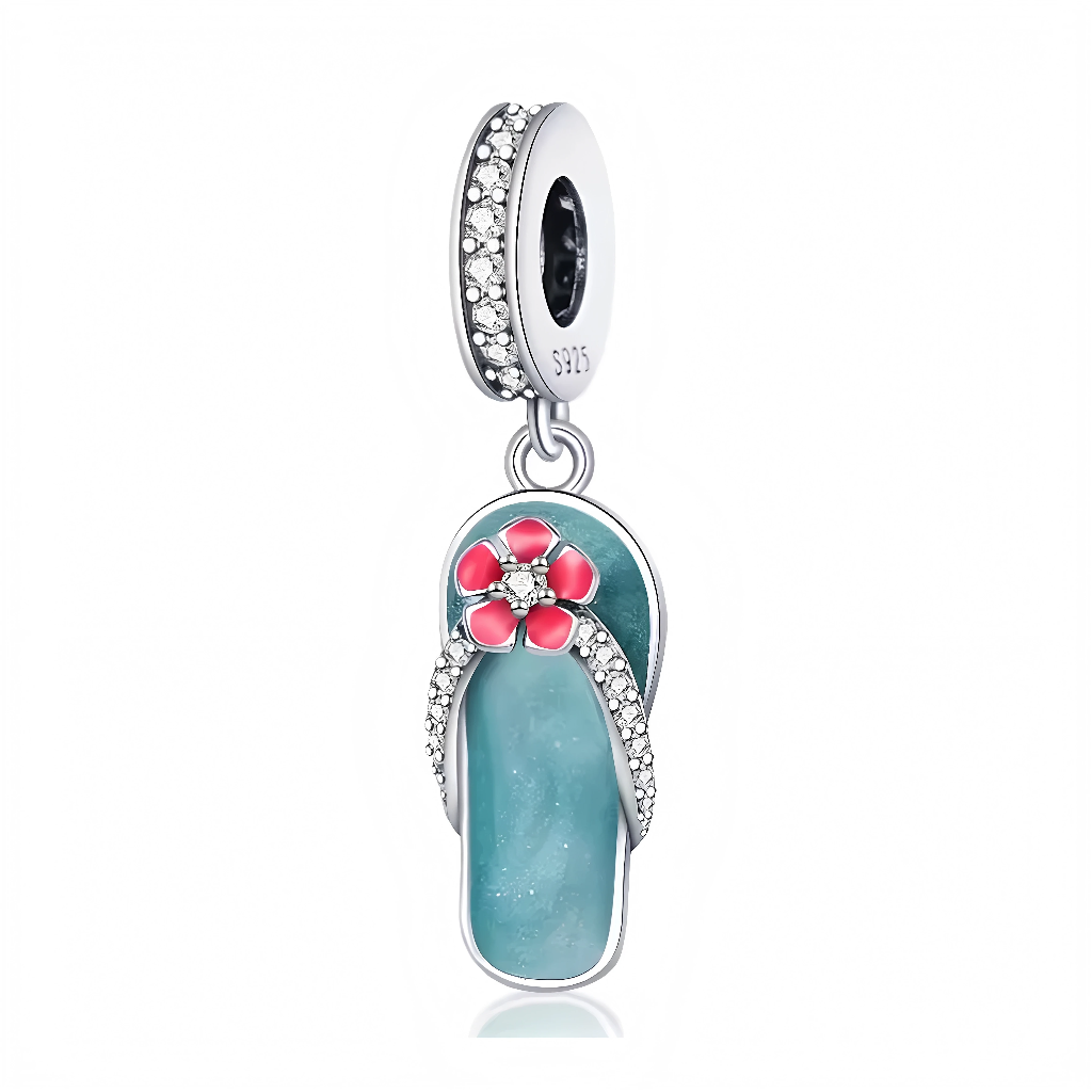 Ce charm pendentif capture l’esprit des vacances avec une tong miniature en émail turquoise brillant, ornée d’une fleur rose éclatante sertie de zircons étincelants au centre. Des zircons fins pavent les lanières et les contours, apportant une touche luxueuse et scintillante à ce motif estival iconique. L’anneau supérieur rond assure une fixation sécurisée et élégante sur les bracelets.