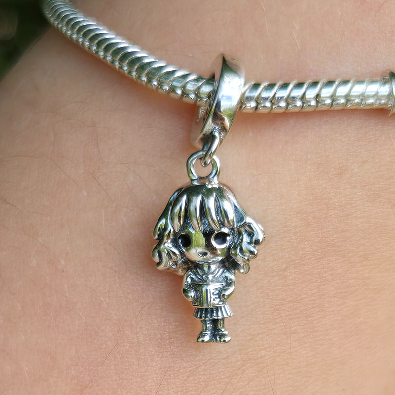 Ce charm en argent 925 montre jeune fille cheveux bouclés robe uniforme tenant livre yeux pétillants mains poche. Symbole intelligence audace érudition magique.

Caractéristiques

Matière : Argent 925.
Design : Style chibi détaillé livre texturé posture confiante.
Compatibilité : Bracelets colliers thèmes scolaires sorciers.