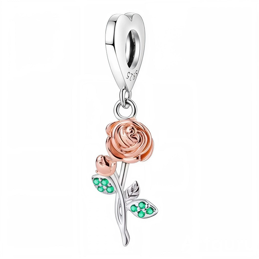 Célébrez la beauté intemporelle avec ce charm pendentif rose, délicatement sculpté en argent et orné d’une finition dorée rose sur la fleur. Les feuilles raffinées rehaussées de petites pierres vertes façon émeraude ajoutent une note de fraîcheur et d’éclat naturel à ce bijou.