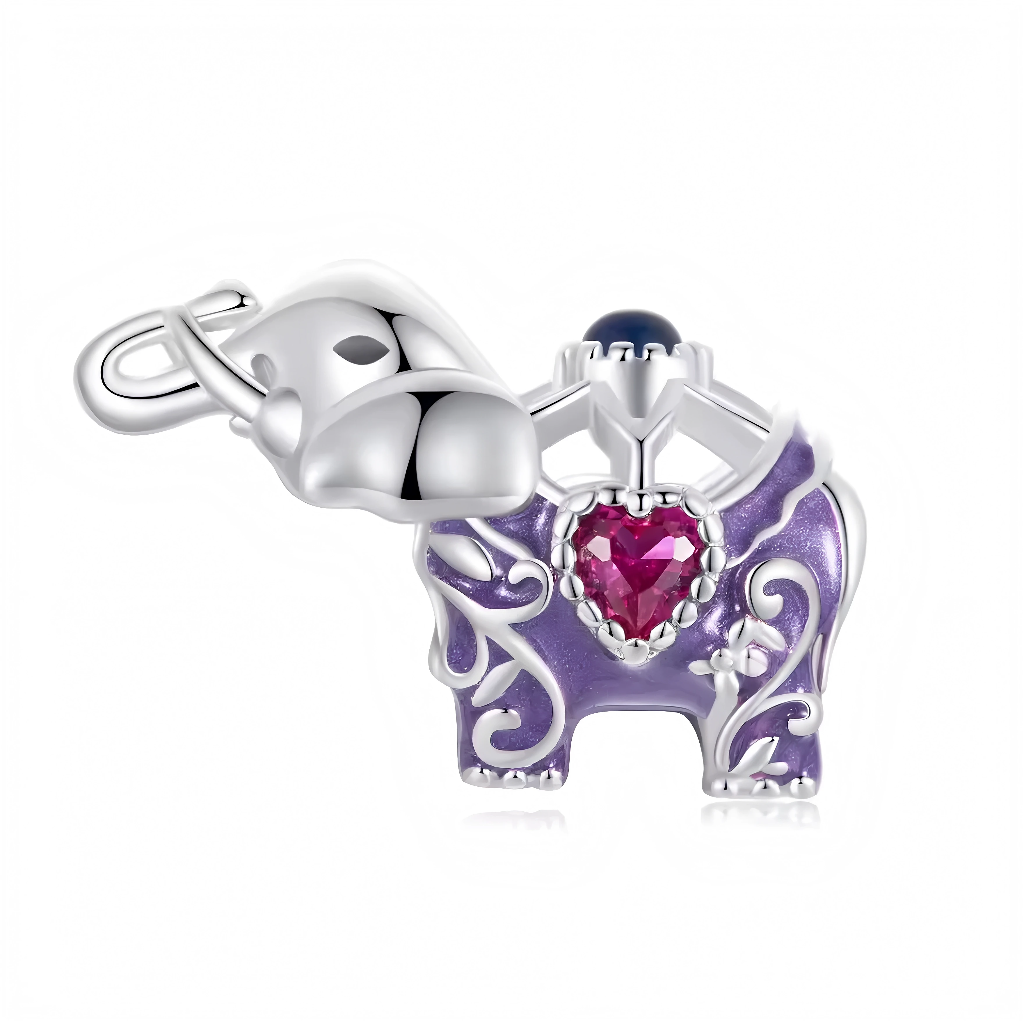 Ce charm pendentif met en scène un éléphant argenté majestueux juché sur un trône violet en émail, orné de motifs floraux baroques et d’un cœur rose serti au centre pour une aura royale et enchantée. La trompe relevée joyeusement, l’œil noir pétillant et les oreilles déployées ajoutent du caractère à cette figure symbolique de sagesse. Le dôme bleu serti surplombe le tout comme une couronne précieuse.