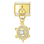 Ce charm italien pendentif représente une jolie tortue, symbole de sagesse et de longévité. Avec sa finition dorée éclatante, il est fabriqué en acier inoxydable de haute qualité pour offrir robustesse et élégance. Facile à fixer, il s’adapte parfaitement à nos bracelets composés de 17 maillons extensibles et réglables, convenant à toutes les tailles de poignet. Compatible avec tous nos charms italiens, ce bijou raffiné est idéal pour personnaliser votre bracelet avec une touche marine et intemporelle.