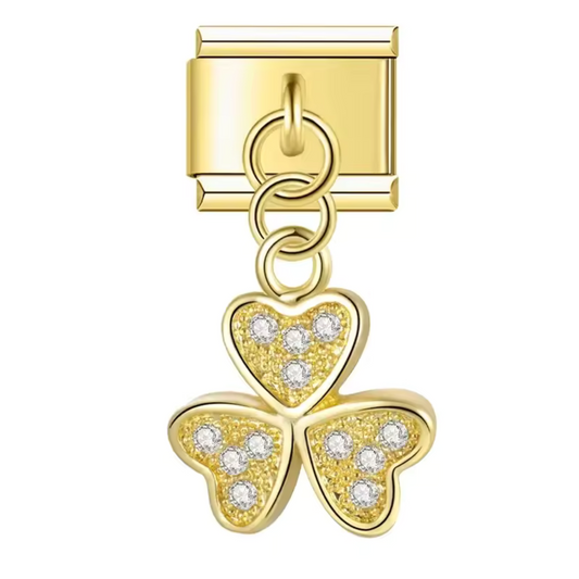 Ce charm italien pendentif doré en forme de trèfle à 3 feuilles est délicatement orné d’une pierre blanche scintillante au centre. Fabriqué en acier inoxydable de haute qualité avec une finition dorée élégante, il allie robustesse et raffinement. Ce pendentif s’attache facilement à vos bracelets ou colliers, offrant une touche de chance et d’élégance. Tous nos charms italiens sont compatibles entre eux, vous permettant de personnaliser votre bijou selon vos envies.