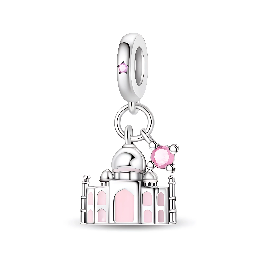 Ce charm pendentif en argent 925 représente une miniature stylisée du Taj Mahal, avec ses dômes et minarets finement sculptés, soulignés d’un émail rose tendre dans les arches et les fenêtres. Un petit cristal rose rond accompagne le monument et un autre orne la bélière, ajoutant une touche lumineuse et féminine à ce symbole d’amour éternel.